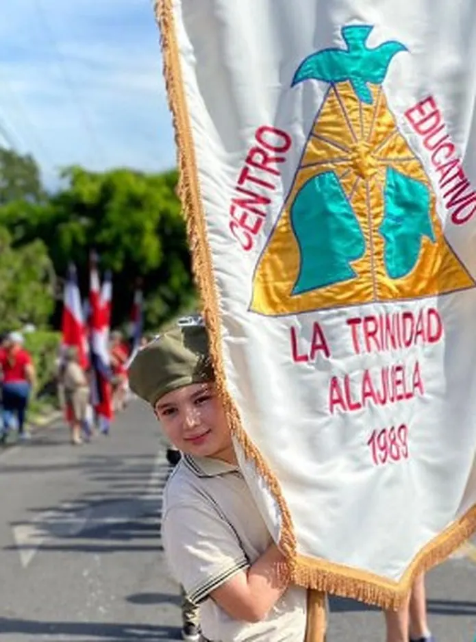 Estudiante de Centro Educativo La Trinidad porta el estandarte institucional en un desfile
