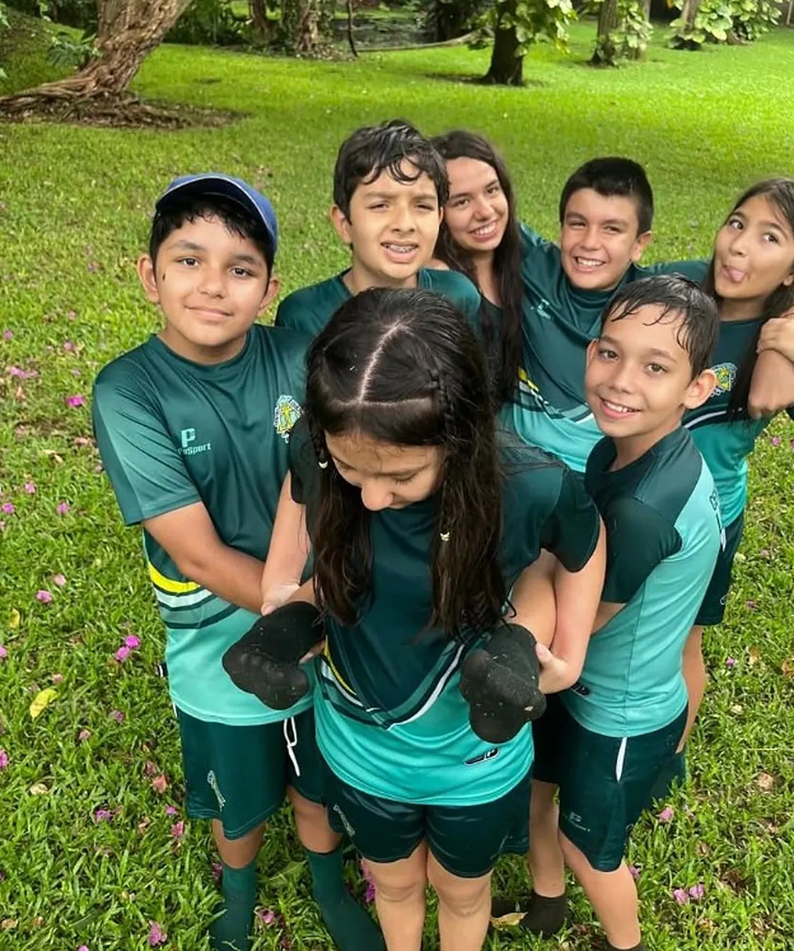 Estudiantes de Centro Educativo La Trinidad en uniforme deportivo verde, juntos después de una actividad al aire libre